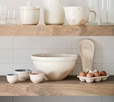 bowls, measuring cups and spoons are sitting on the shelf