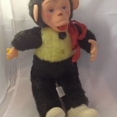 a stuffed monkey wearing a yellow shirt and black pants with a red ribbon around its neck