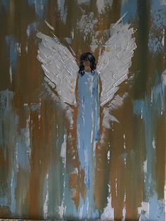 an angel painted on the side of a building with blue paint and white wings above it