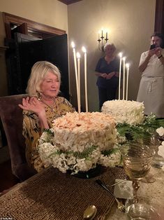 a woman sitting at a table in front of a cake with lit candles on it