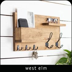 a wooden wall mounted shelf with key hooks and glasses hanging on it's side