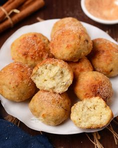 a white plate topped with donuts covered in powdered sugar next to cinnamon sticks