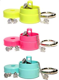 four different colored jewelry containers with rings and chains on them, all stacked up in the same row