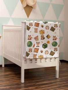 a baby crib with an owl themed blanket on it's top, next to a wooden floor