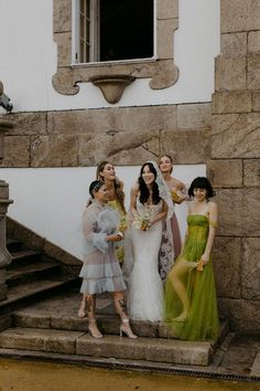 a group of women standing next to each other in front of a stone building with stairs