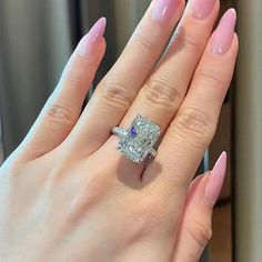 a close up of a person's hand with a ring on her finger and an engagement ring in the other hand