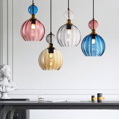 three multicolored glass pendant lights hanging from a ceiling fixture over a dining room table