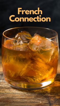 a glass filled with ice sitting on top of a wooden table