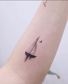 a small sailboat tattoo on the left arm is shown in black and grey ink