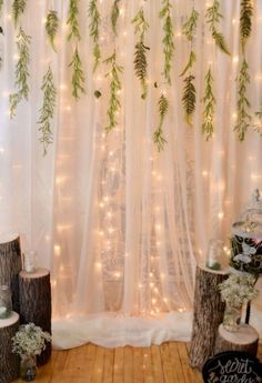 a white curtain with lights and greenery hanging from it's sides in front of a window