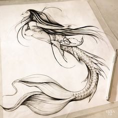 a drawing of a woman with long hair and fish tail, sitting on top of a piece of paper