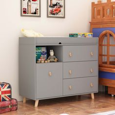 a grey dresser with two pictures on the wall above it and a teddy bear next to it