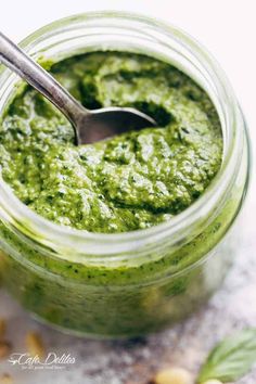 a spoon in a jar filled with pesto