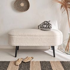 a white bench sitting on top of a rug next to a vase