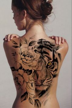 a woman's back with a tiger and roses tattoo on her upper half body