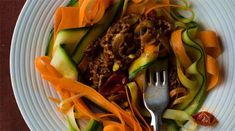 a white plate topped with lots of veggies next to a fork and knife