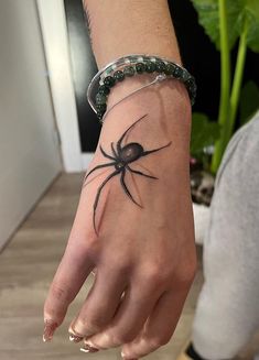 a hand with a black spider tattoo on it's left arm and the wrist