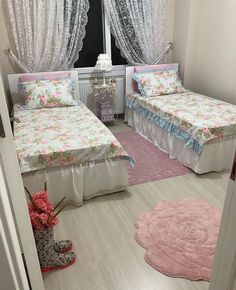 two beds in a room with pink rugs and curtains