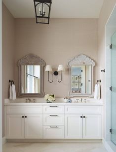 a bathroom with double sinks and two mirrors on the wall next to a walk in shower