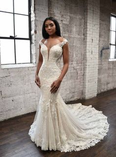 a woman in a wedding dress standing on a wooden floor next to a brick wall