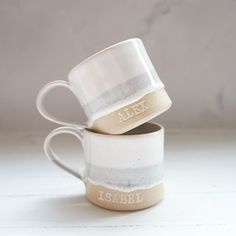 two coffee mugs stacked on top of each other with the word alex printed on them