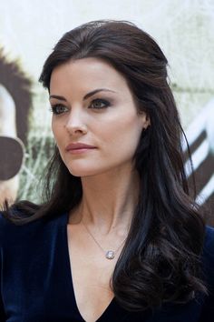 a woman with long dark hair wearing a black dress