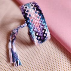 a close up of a tie on top of a pink cloth with tassels