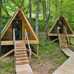 two wooden cabins in the woods with stairs leading up to them