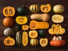 pumpkins and gourds are arranged on a wooden surface, with one cut in half