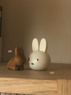 two stuffed animals sitting on top of a wooden shelf