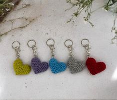 four crocheted heart shaped keychains sitting on top of a white surface