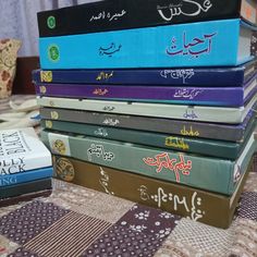 a stack of books sitting on top of a bed next to a book bag with arabic writing