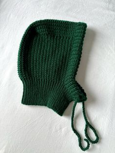 a green knitted hat laying on top of a white sheet