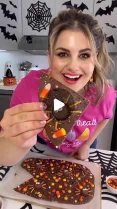 a woman holding up a halloween treat in front of a table with candy and candies