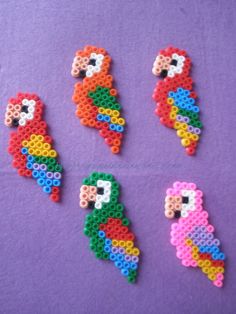 four different types of beaded parrots on a purple surface