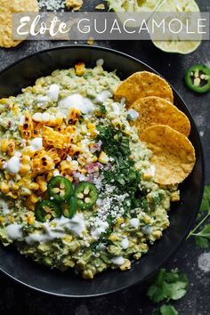 a black plate topped with guacamole and tortilla chips next to cilantro