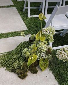 chairs are set up on the grass for an outdoor ceremony with flowers and greenery