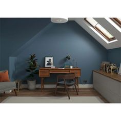 an attic office with blue walls and wooden desk in the corner, along with a gray chair