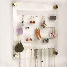 a white wall mounted jewelry rack with lots of earrings