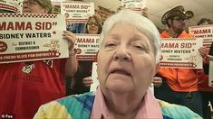 an older woman holding up signs in front of her face while others hold their hands behind her