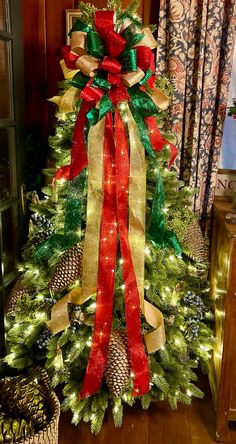 a decorated christmas tree with red, green and gold ribbons on it's bow