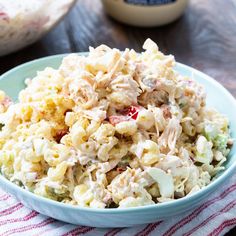 a blue bowl filled with chicken salad on top of a table