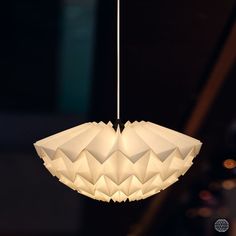 an origami light hanging from a ceiling in a dark room with other lights