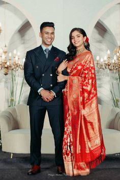 a man and woman standing next to each other in front of a chandelier