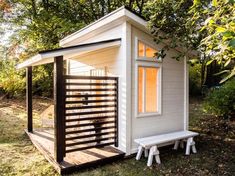 a small white shed with a bench in front of it