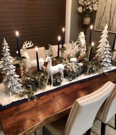 a dining room table decorated for christmas with candles, ornaments and deer figurines