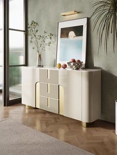 a white and gold sideboard in a living room with a potted plant next to it