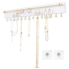 a white wall mounted jewelry rack with gold chains and earring hooks hanging from it