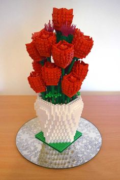 a white vase filled with red flowers on top of a table