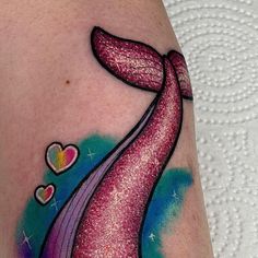 a colorful tattoo on the arm of a woman with hearts and a whale tail painted on it